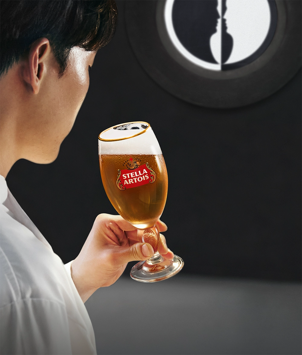 스텔라 아르투아 협찬 받은 넷플릭스 흑백요리사 시즌 2 무대 배경에 백 요리사가 챌리스 전용잔에 담긴 생맥주를 마시고 있습니다.